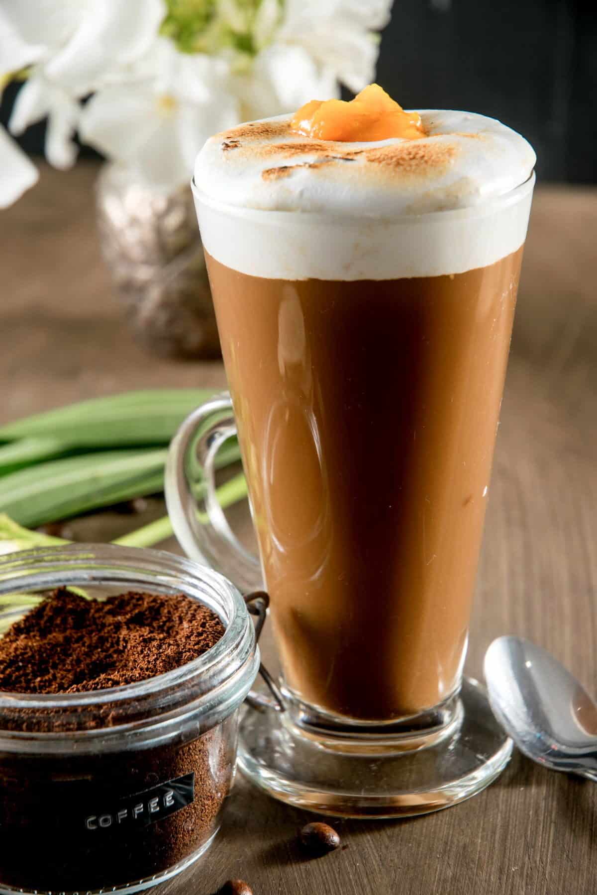 Marshmallow pumpkin latte in a mug, coffee grind on the side.