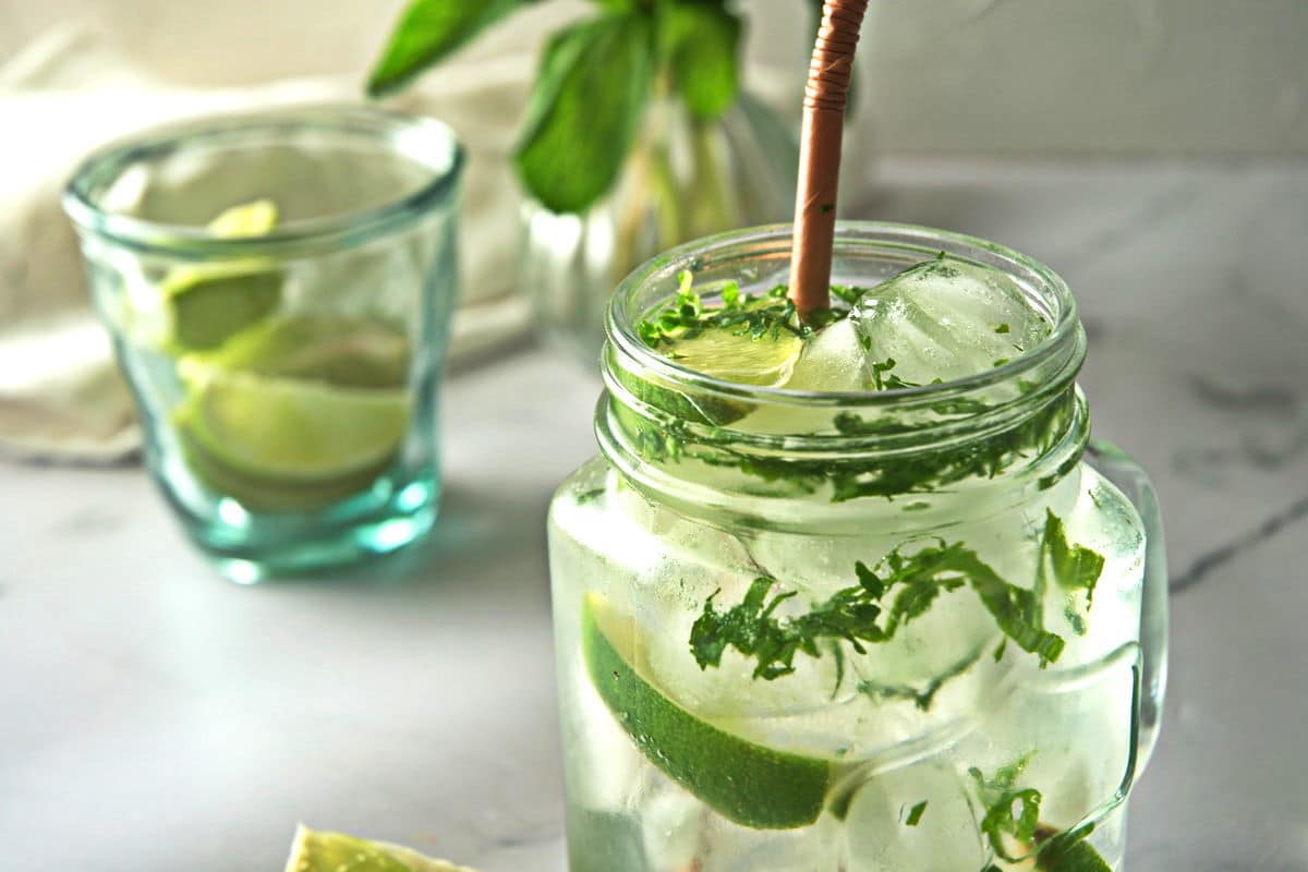 Mojito mocktail in a glass mug with a brown straw.