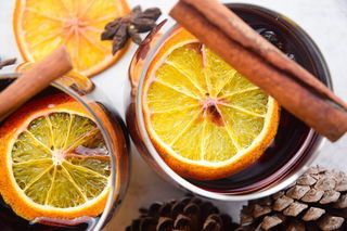 Electric Skillet Mulled Wine in wine glasses with orange slices and cinnamon sticks, acorns in the background.