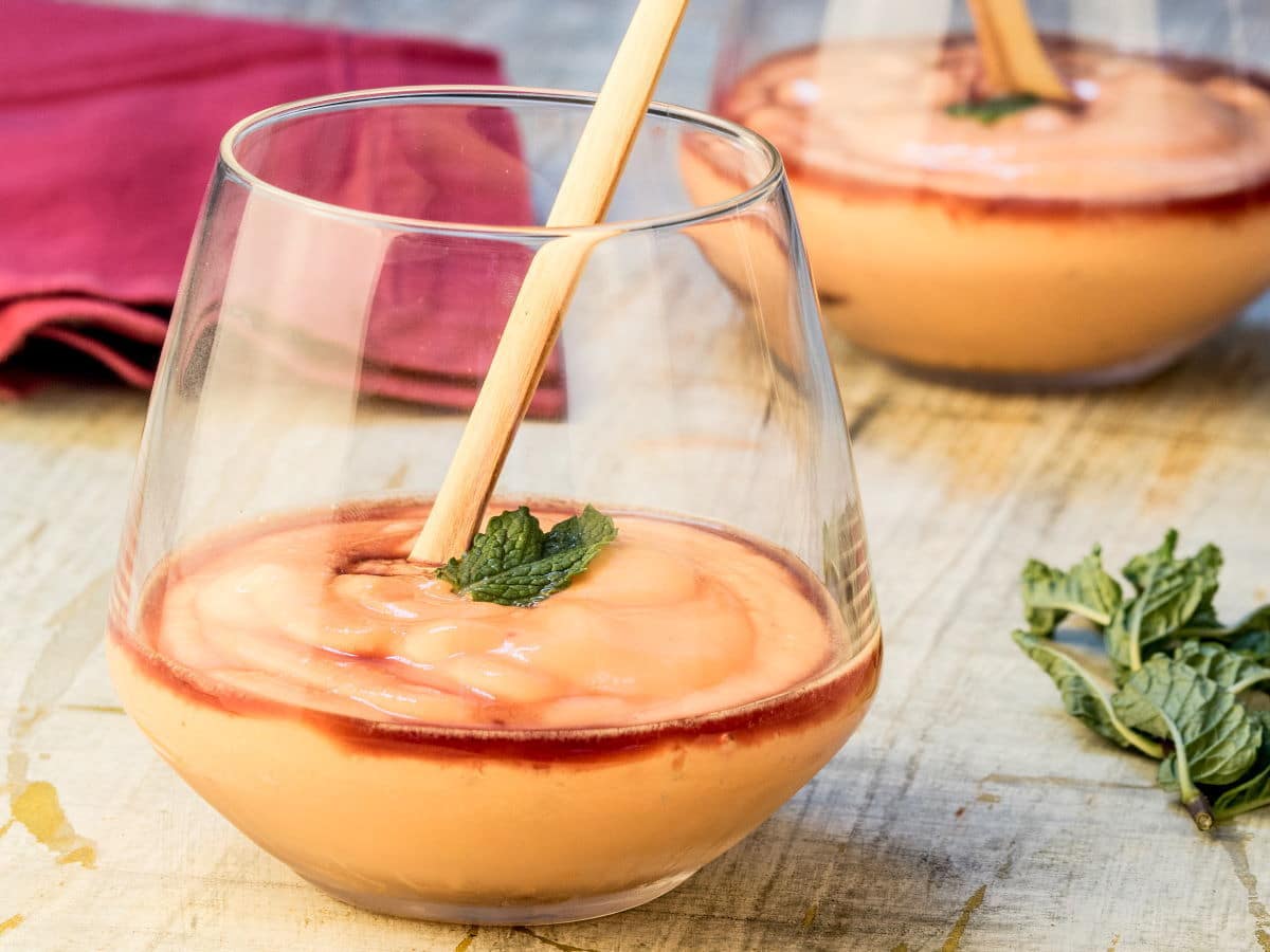 Papaya Cream with Cassis Liqueur in a wine glass with a stir stick.