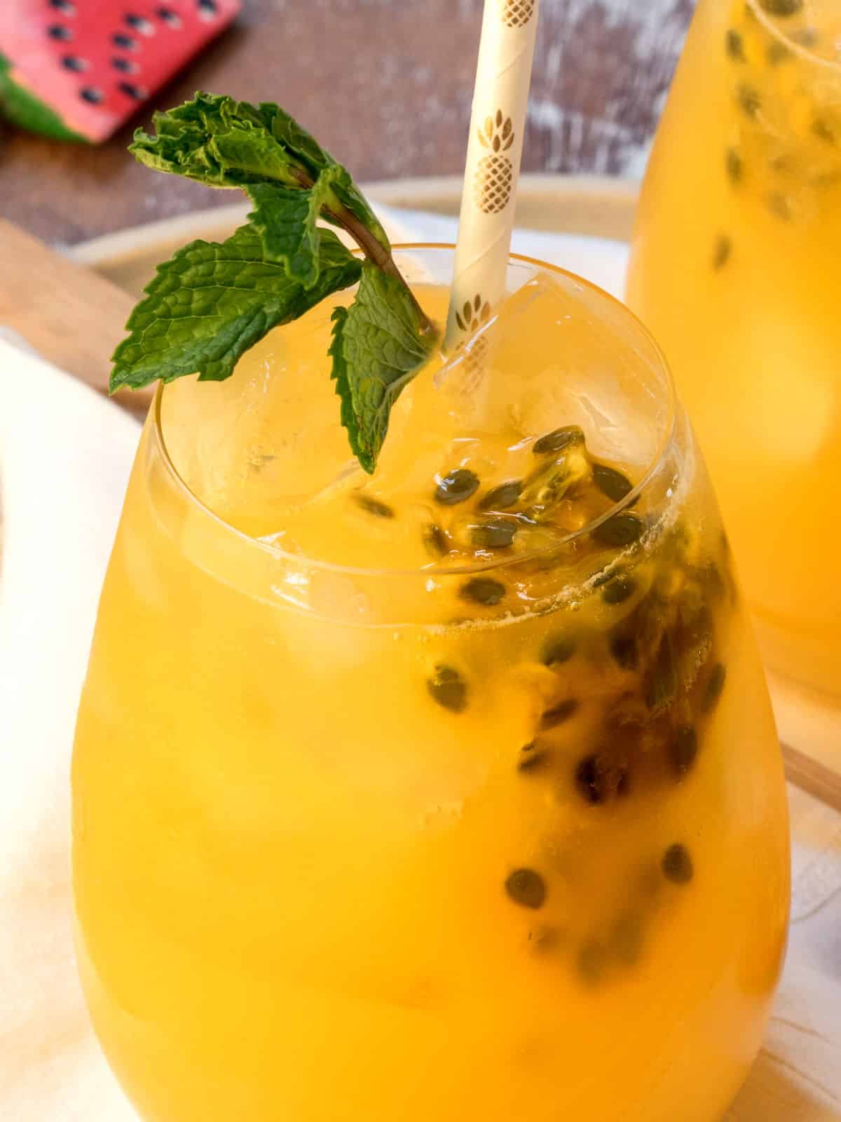 Passion fruit and ginger mojito in a wine glass with white paper straw.