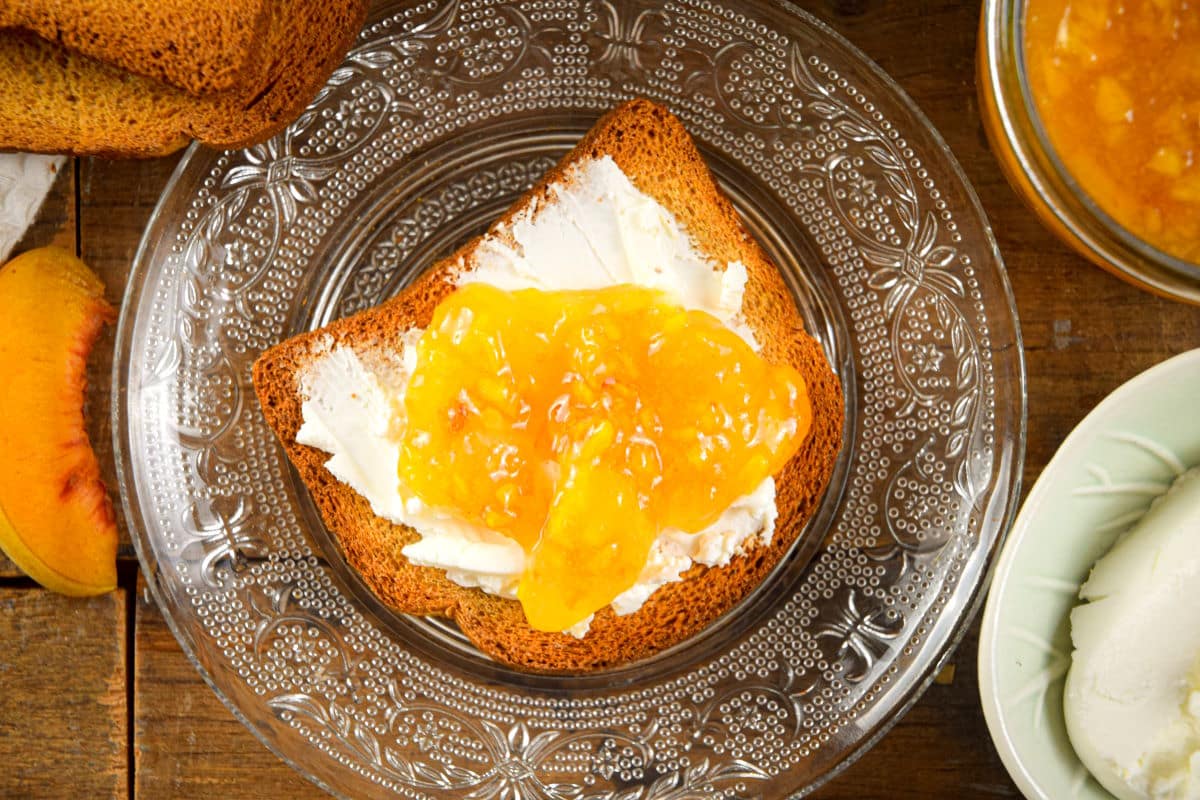 Peach freezer jam and cream cheese on a piece of toast, top view.