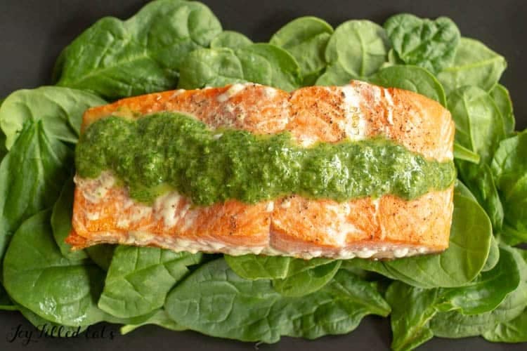 Pesto salmon on bed of greens.