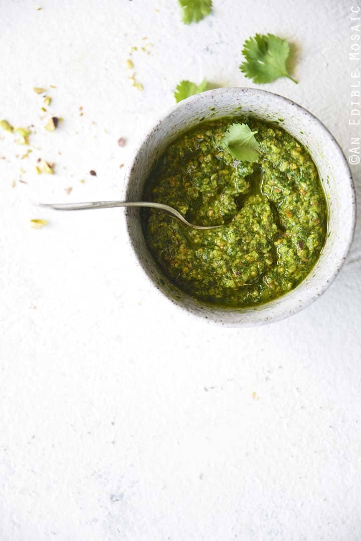 Pistachio cilantro pesto in white rustic bowl on white background.