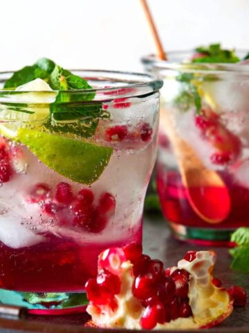Pomegranate mojito mocktails in glasses on tray.