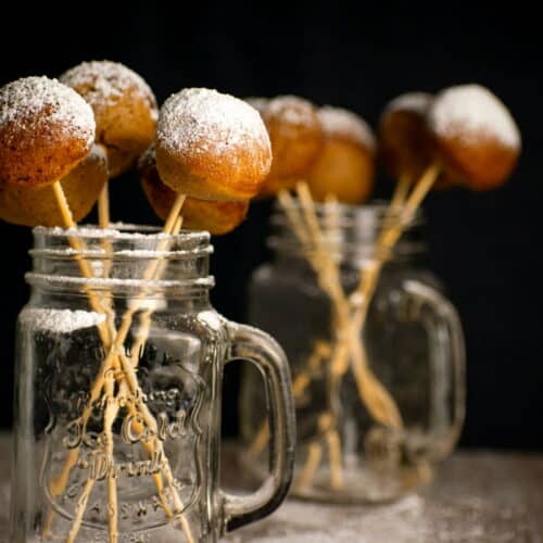 Pumpkin cake pops in jars with powdered sugar. Black background.