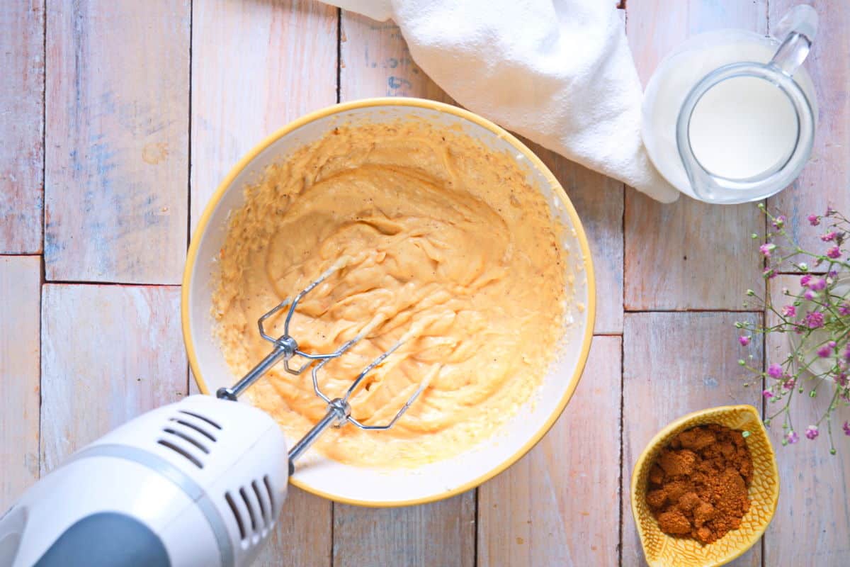 Pumpkin dip in a small bowl with an electric hand mixer.