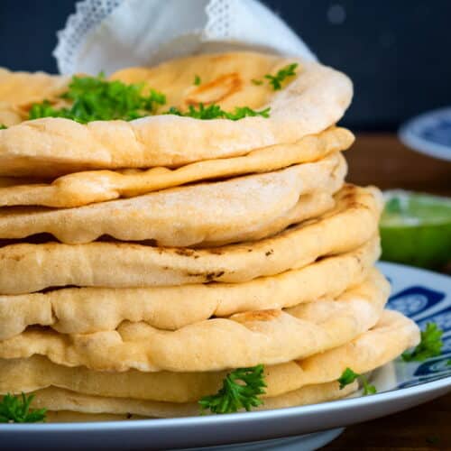 Pumpkin naan bread stacked on a decorative plate.
