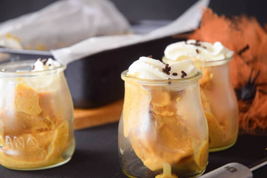 Pumpkin spice ice cream in small glass jars with orange fabric and plastic spiders.