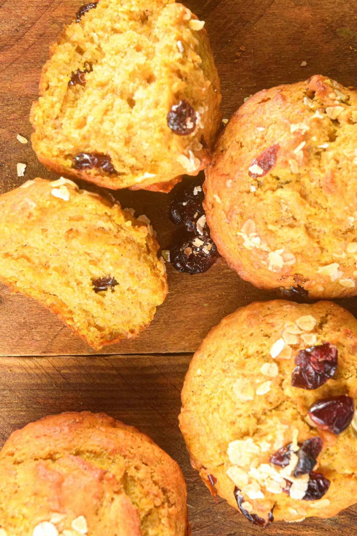Pumpkin muffins with cranberries and oats on wooden background.