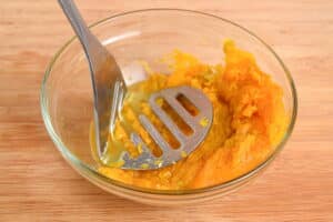 Pumpkin puree in bowl with masher.
