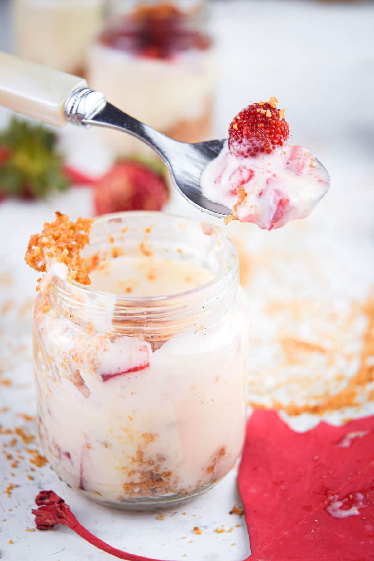 Raspberry cheesecake in mini dessert jar with a spoon.