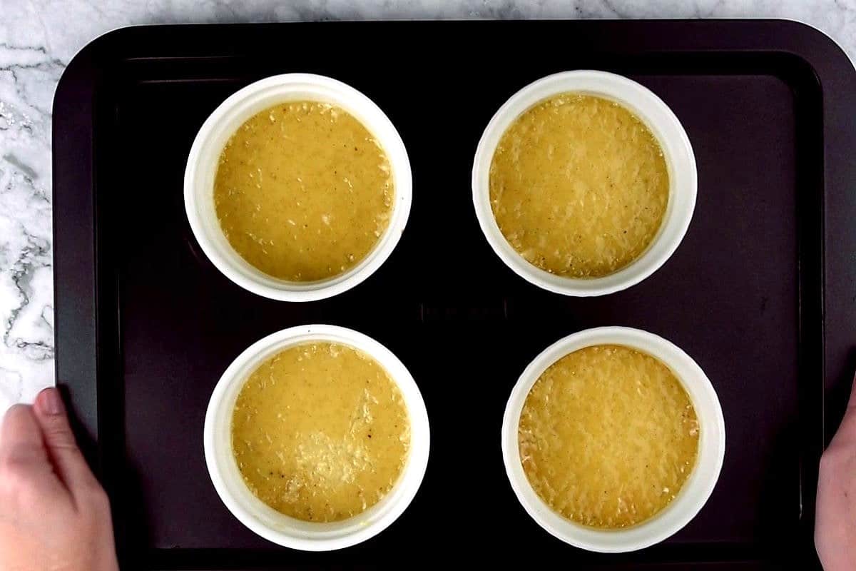 Baked Crème Brûlée in ramekins on sheet pan.
