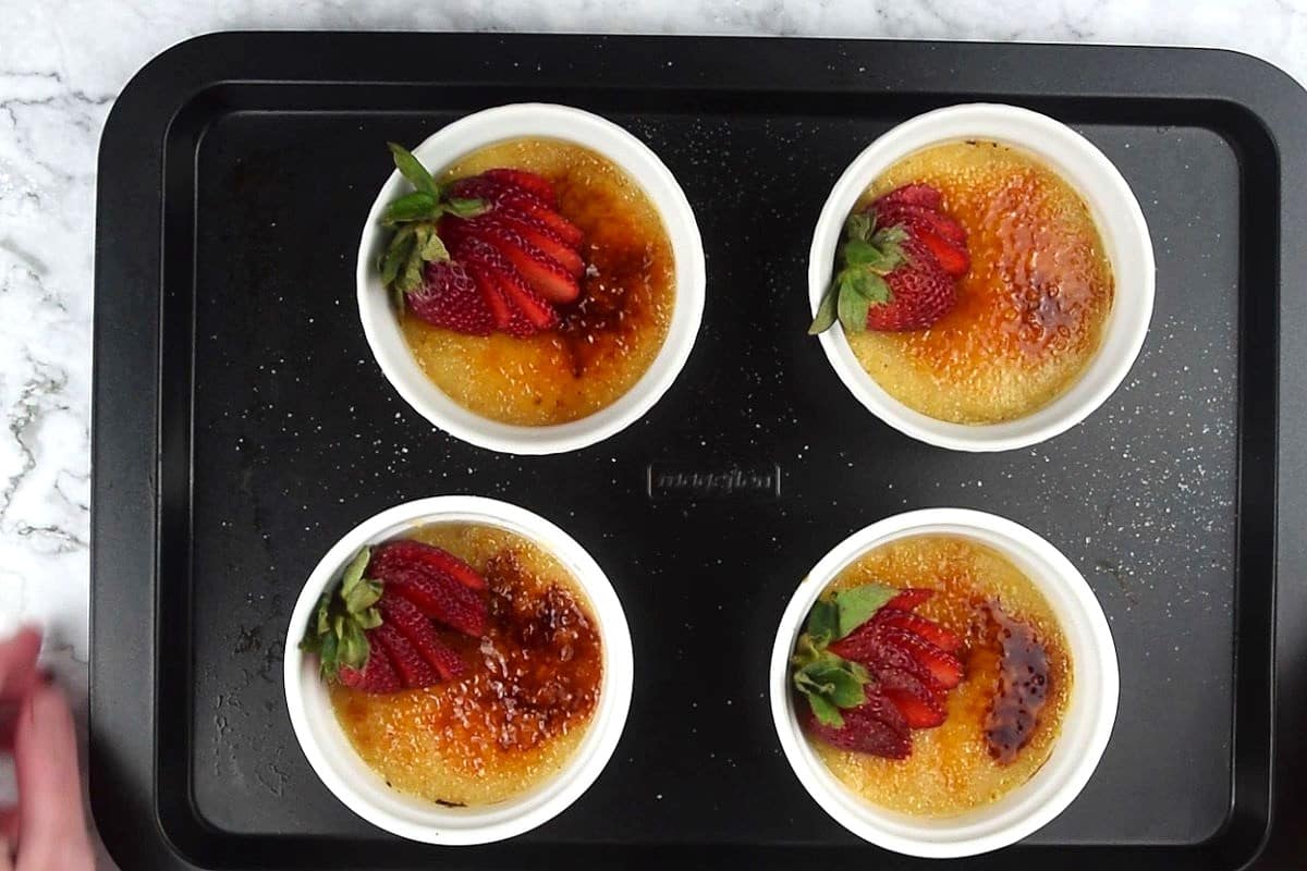 Crème Brûlée with burnt sugar topping and fresh strawberries in ramekins.