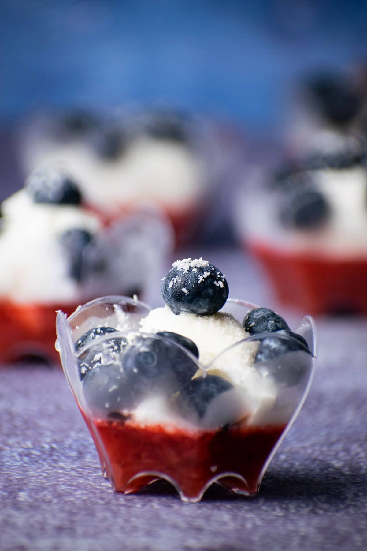Mini fruit and ice cream treat in a dessert cup, with blue background.
