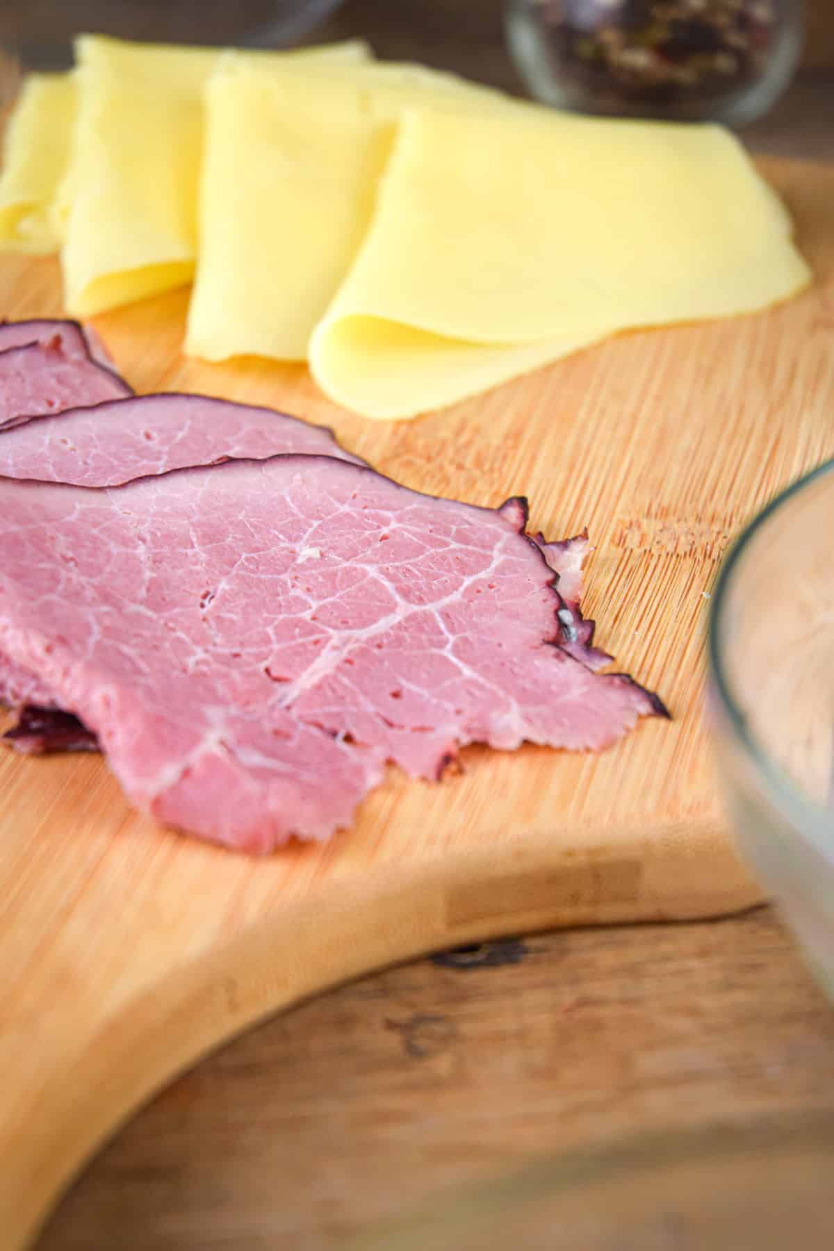 Swiss cheese and corned beef on cutting board.