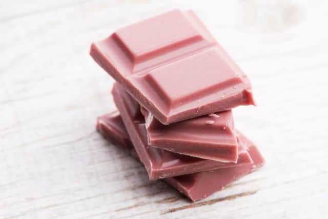 Ruby chocolate pieces, white background.