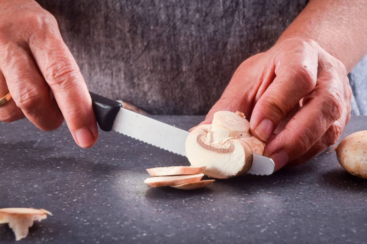 Button mushrooms sliced with knife.