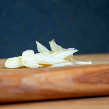 Sliced garlic on cutting board.