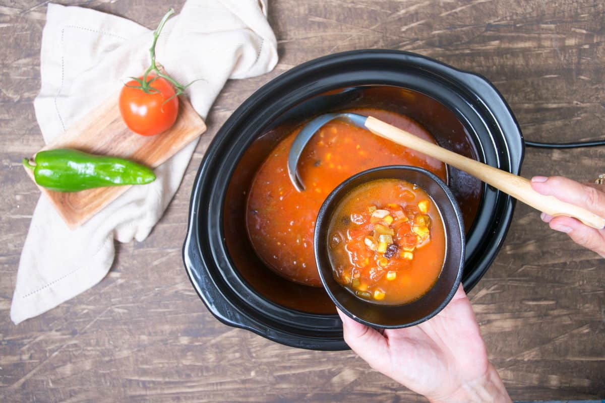 Mexican soup in slow cooker on wooden background.
