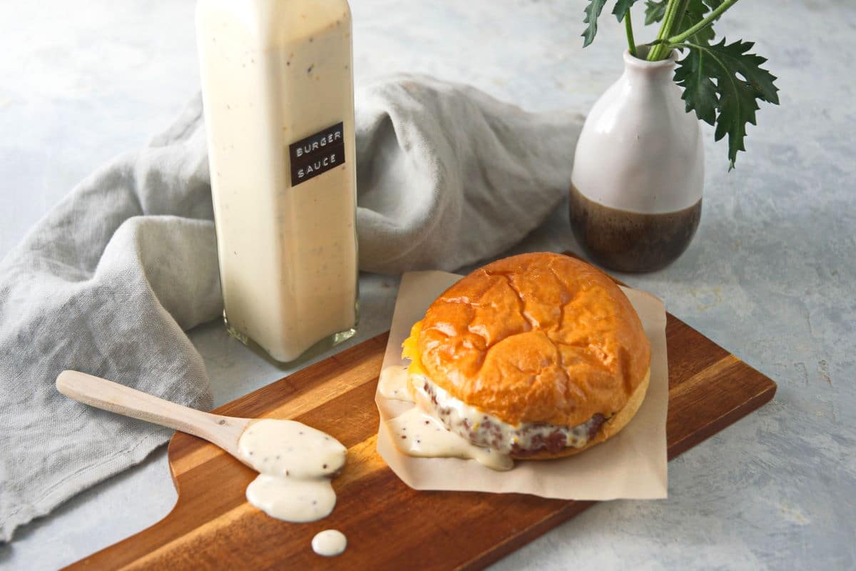 Burger sauce in a bottle with hamburger and spoon.