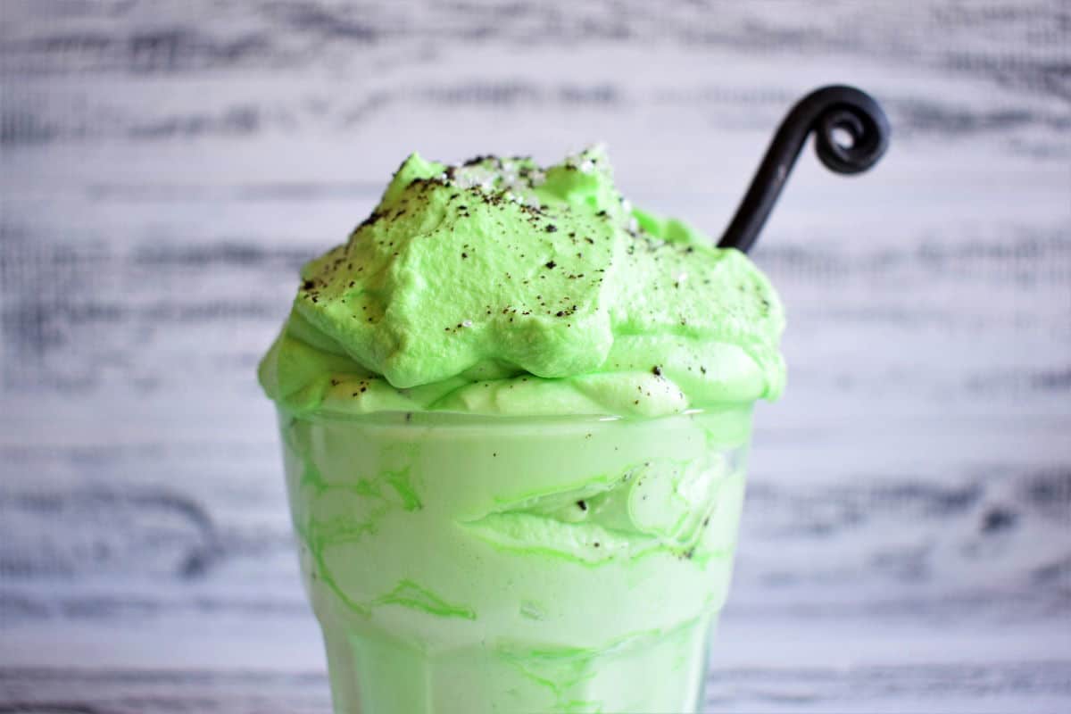 St. Patrick's Day Peppermint Whipped Cream in a glass, white wooden background.