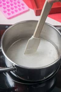 Sugar and syrup mixture in a saucepan with spatula.