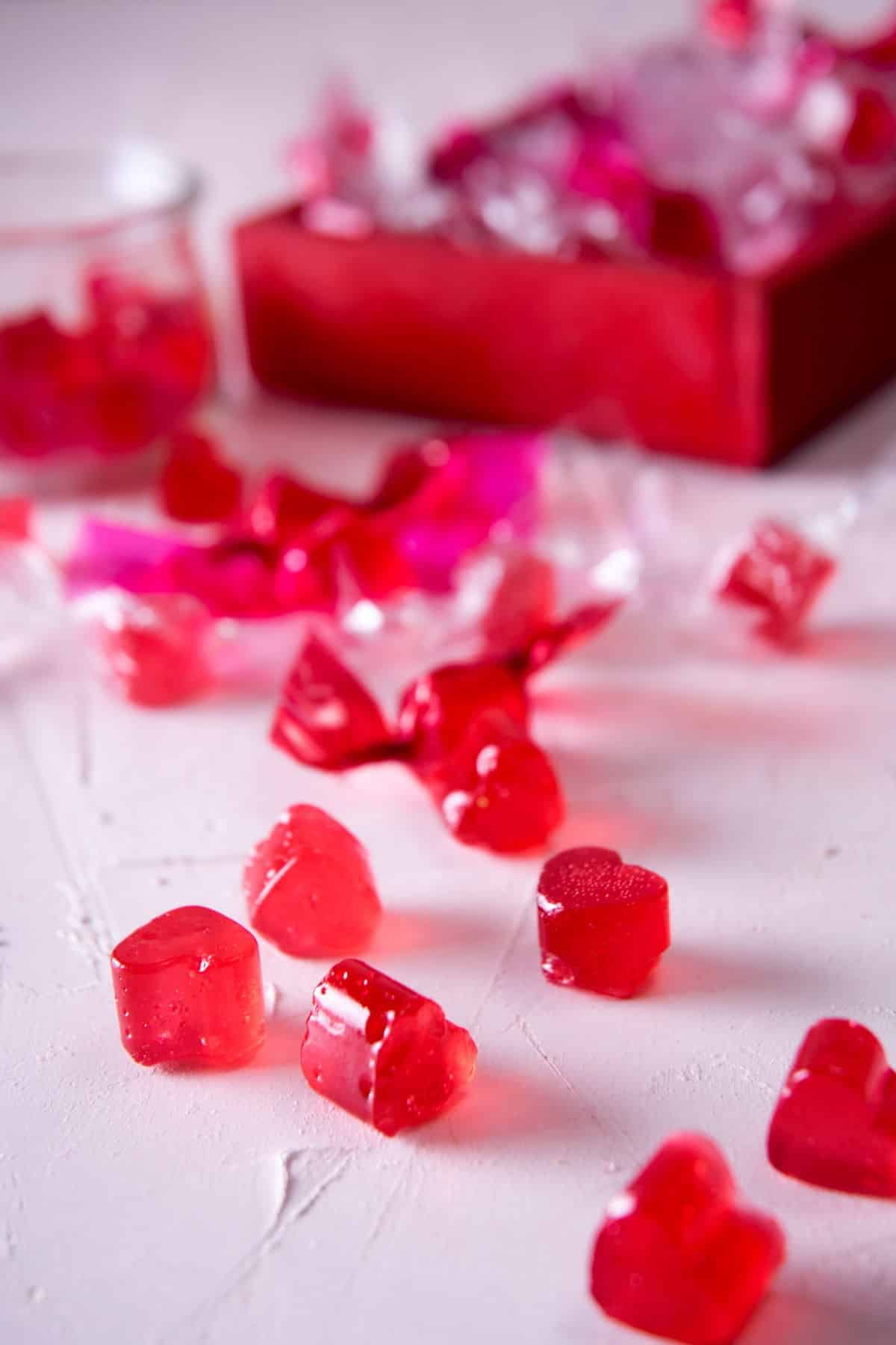 Strawberry hard candies scattered on white surface.