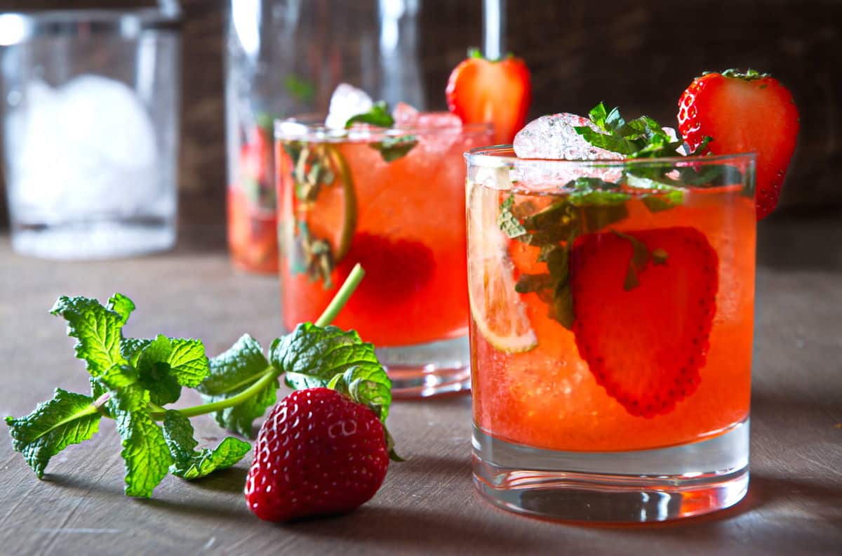 Strawberry mojito mocktails in glasses with fresh strawberries and mint on the side.