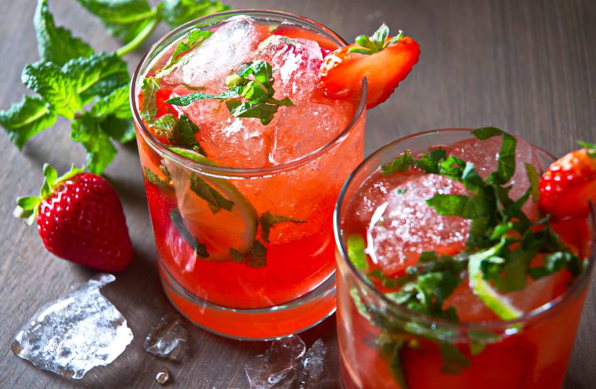 Strawberry mojito mocktails in glasses with fresh strawberries, mint and ice on the side.