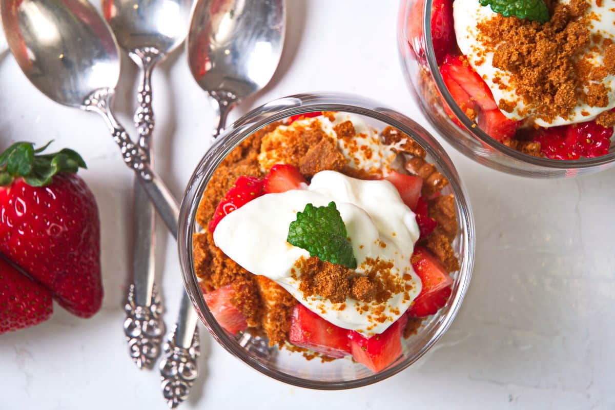 Top view of strawberry parfait in a wine glass with dessert spoons on the side.