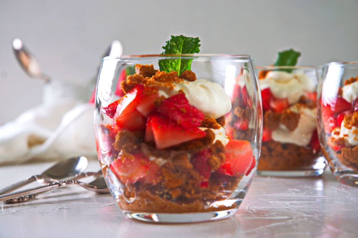 Strawberry parfait in a wine glass with a mint leaf garnish.