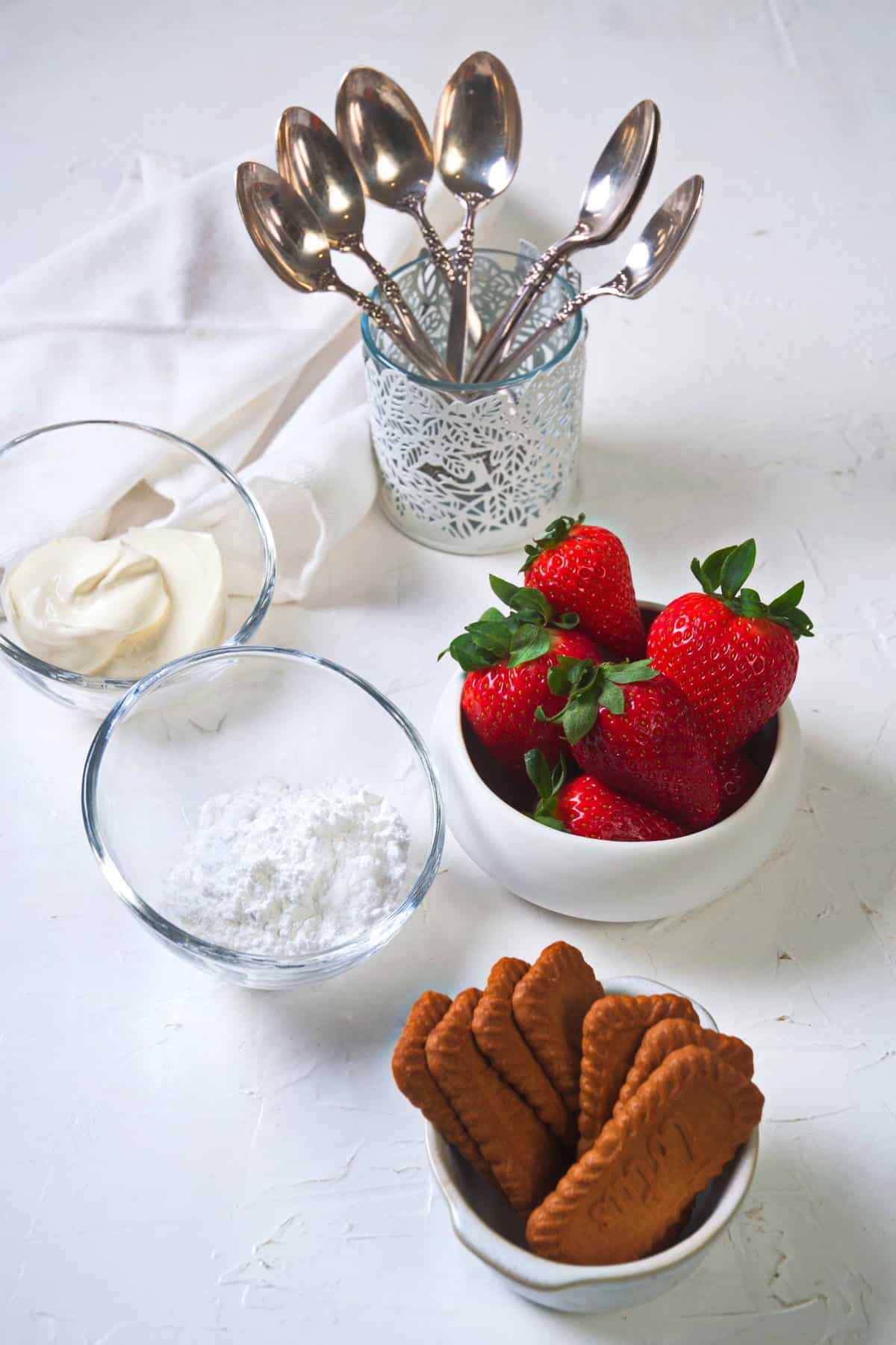 Strawberry parfait ingredients prepped on white background.