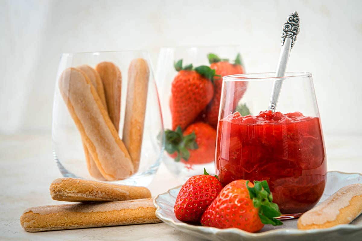 Strawberry-rhubarb sauce in a glass, biscuits on the side.