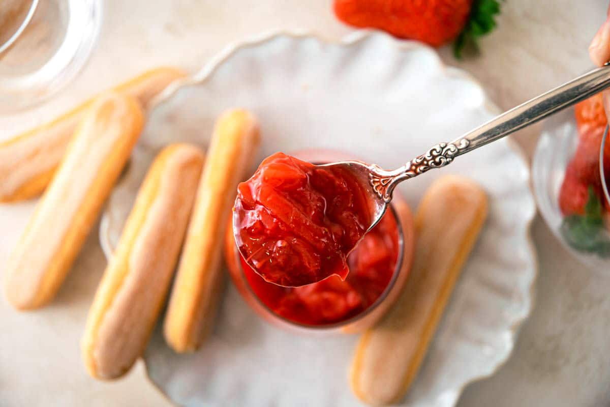 Strawberry-rhubarb sauce in a spoon, biscuits on the side.