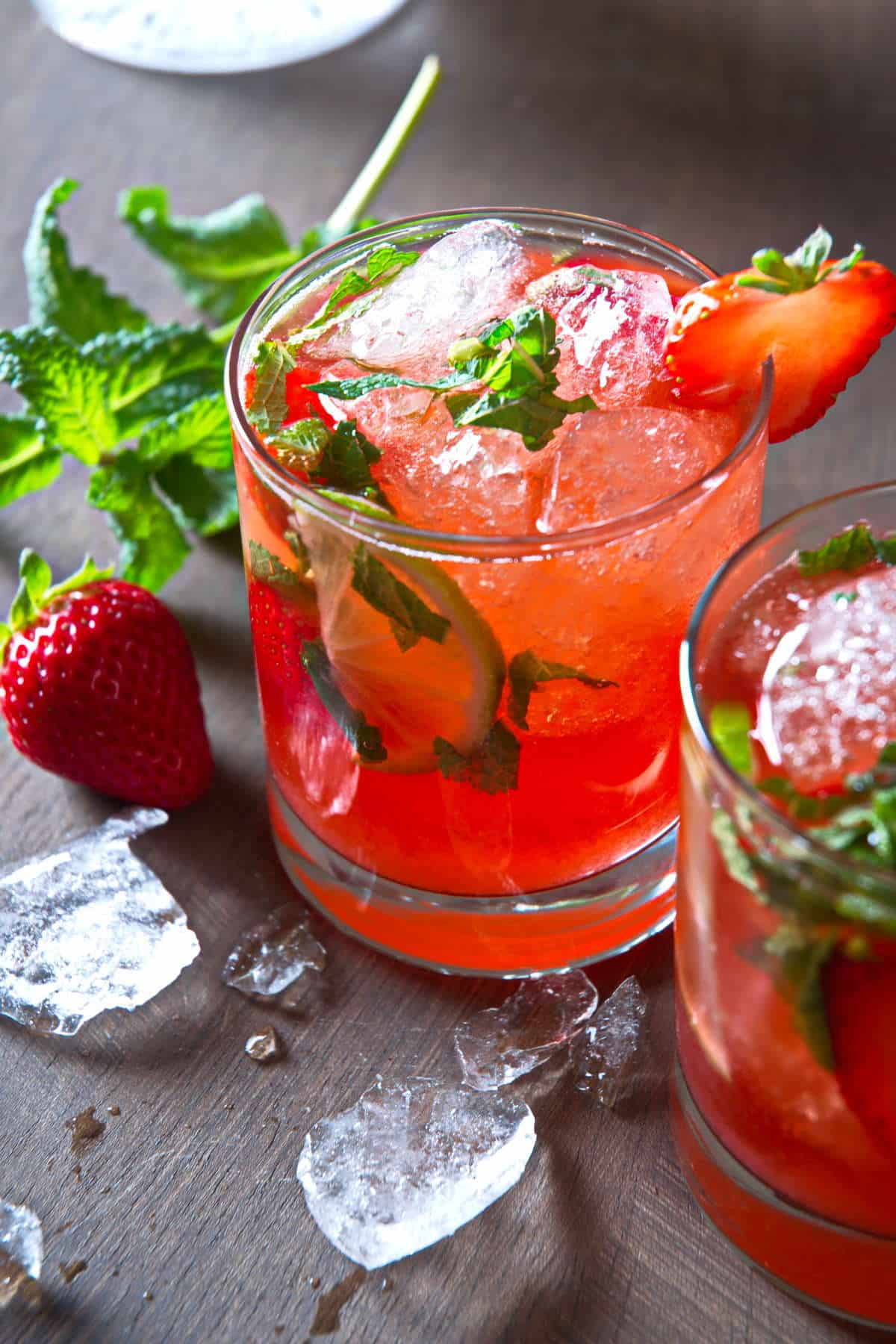 Strawberry mojito mocktail in a glass with fresh strawberries, mint and ice on the side.