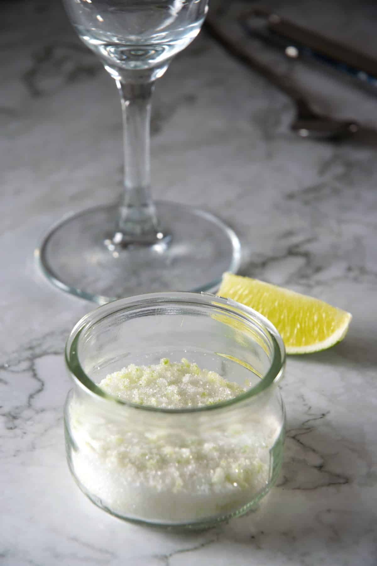 Lime zest sugar rim in a small jar with a lime wedge on the side.