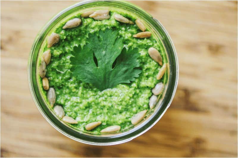 Cilantro pesto with sesame seeds in jar, top view.