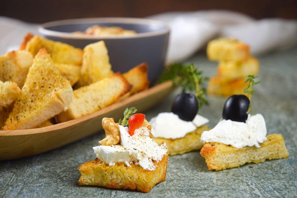 Toast points with cream cheese and black olive toppings.