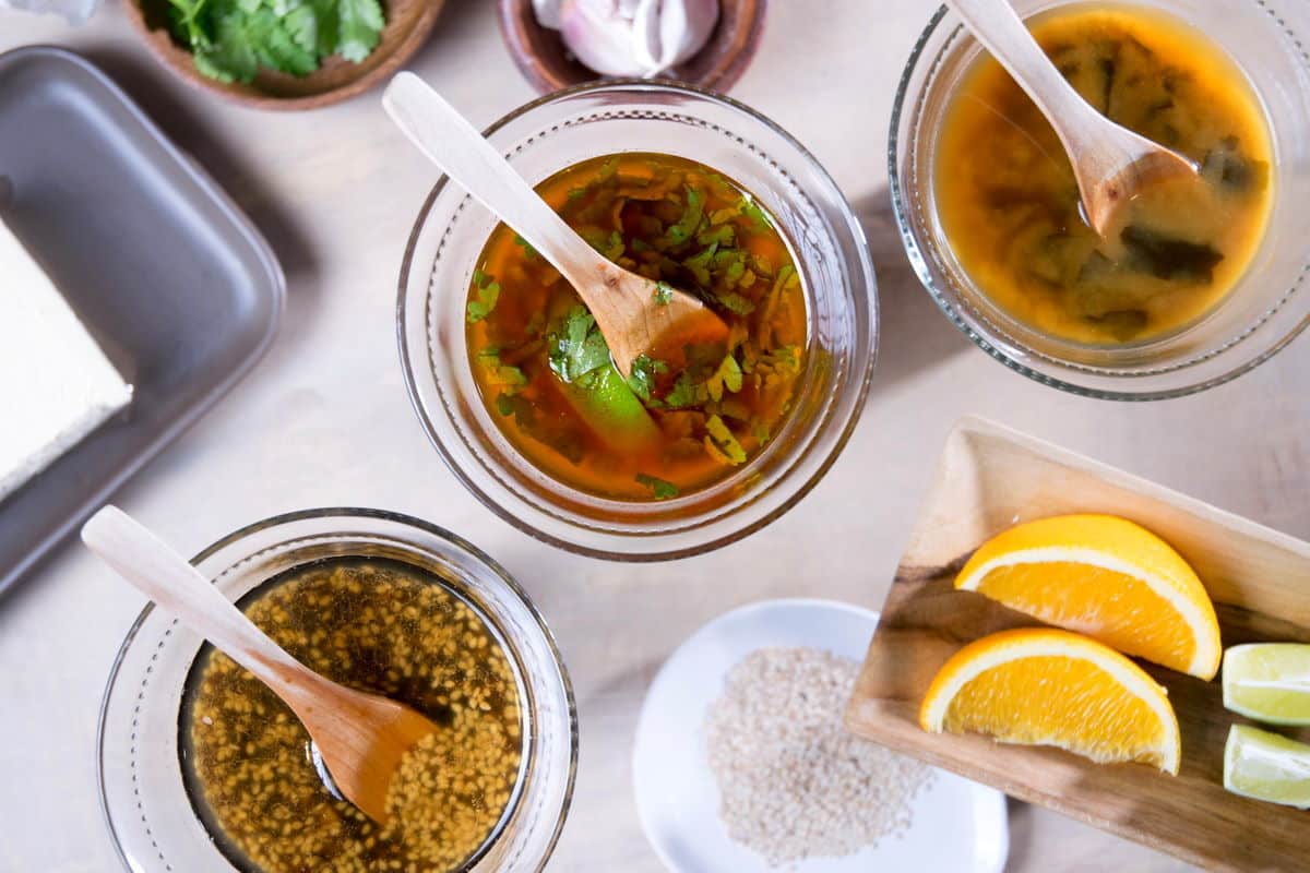 3 tofu marinades in small bowls with spoons.