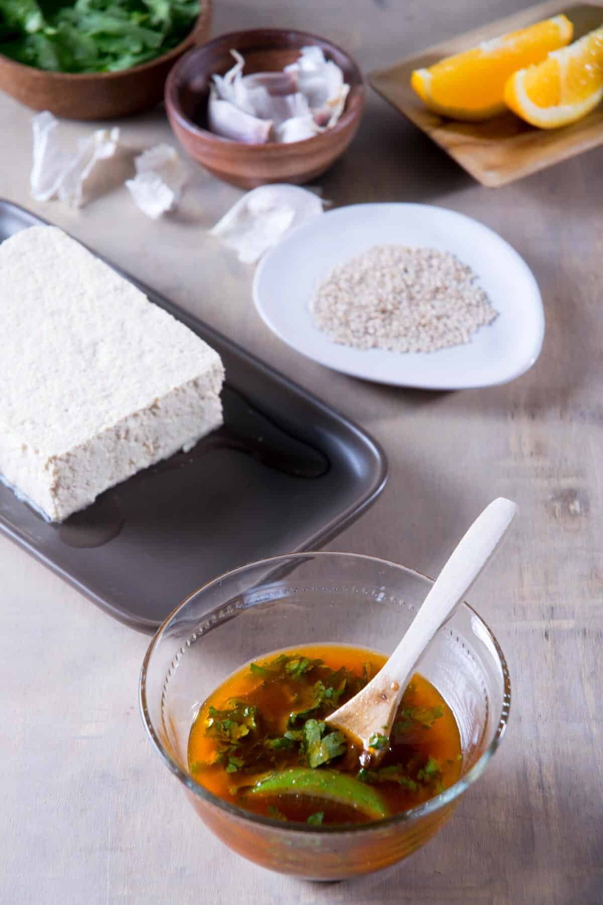 Mexican tofu marinade in a small bowl with a spoon, tofu in the background.