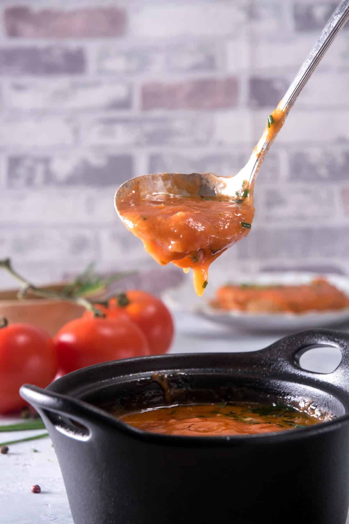 Tomato gravy in a small cast iron bowl and a soup spoon.