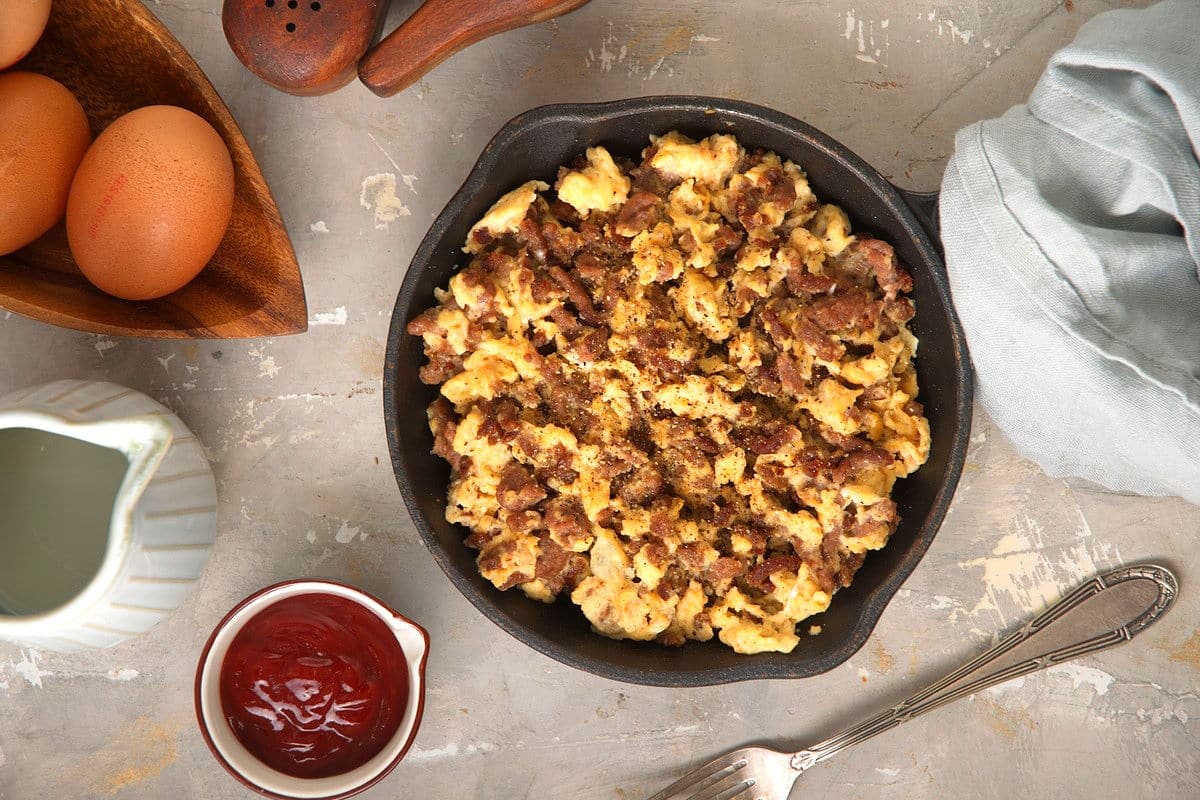 Hamburger scrambled eggs in a cast iron pan with hp on the side.