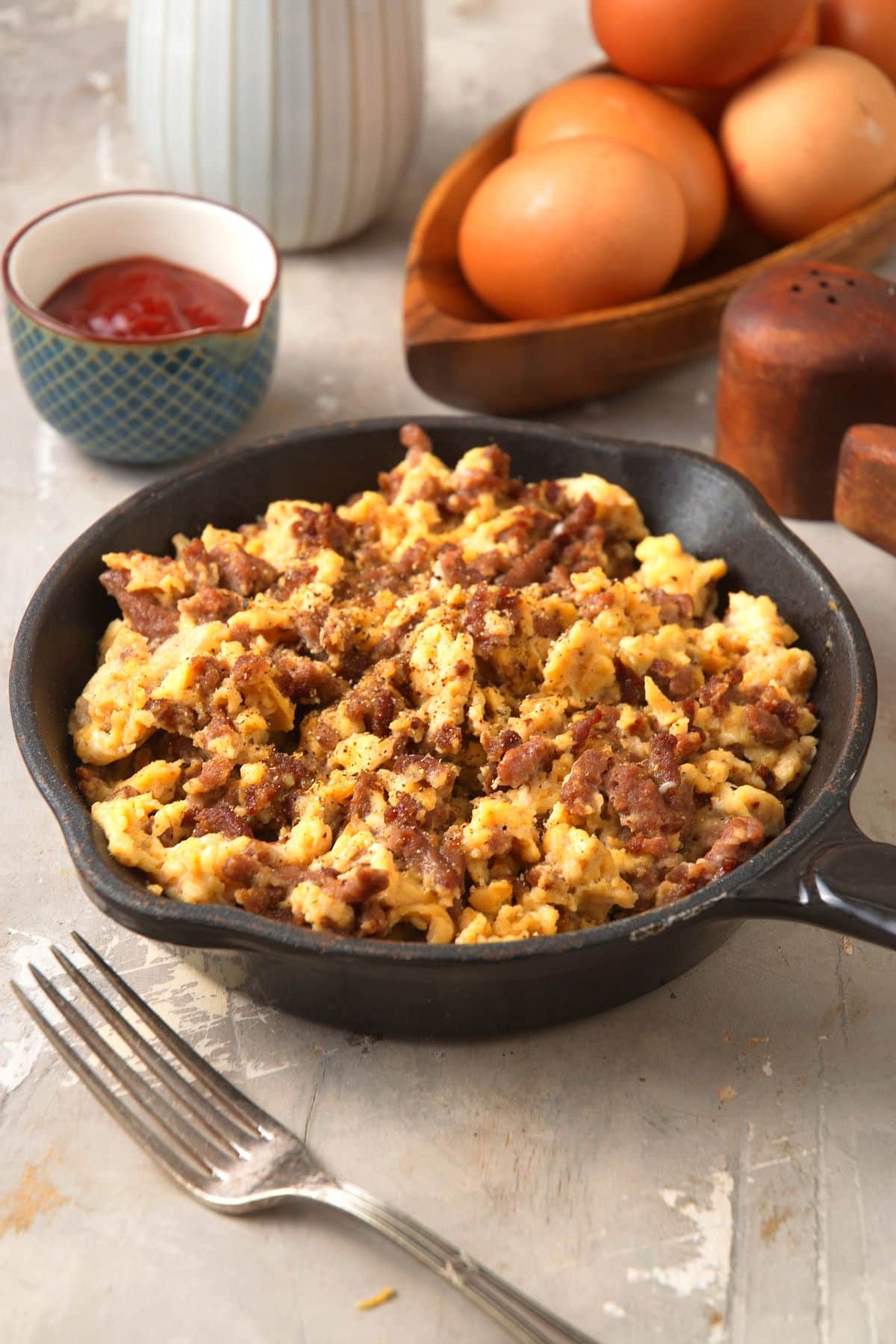 Hamburger scrambled eggs in a cast iron pan with hp in the background.