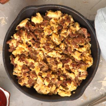 Hamburger scrambled eggs in a cast iron pan with hp on the side.