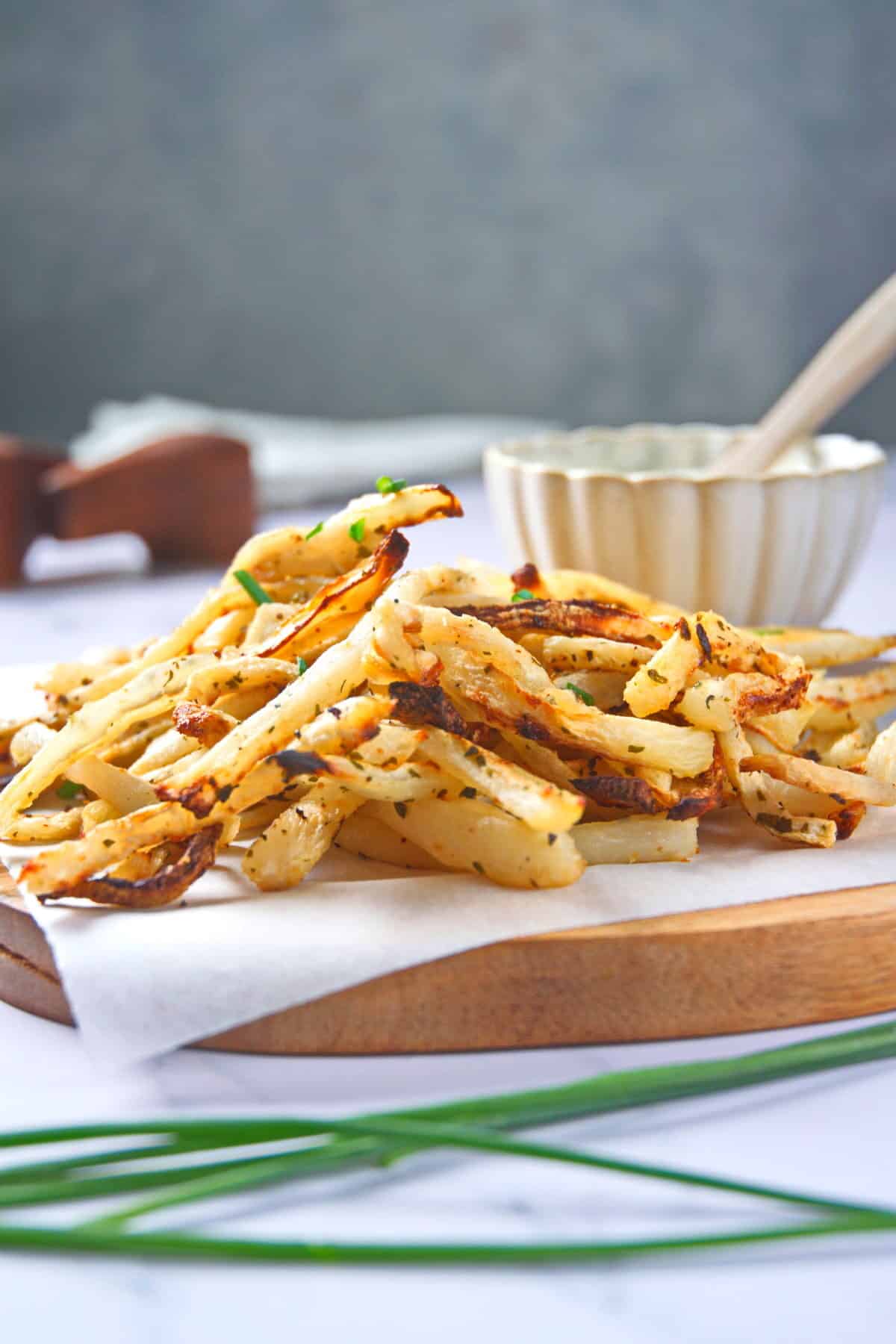 Golden turnip fries on parchment-lined wooden board.