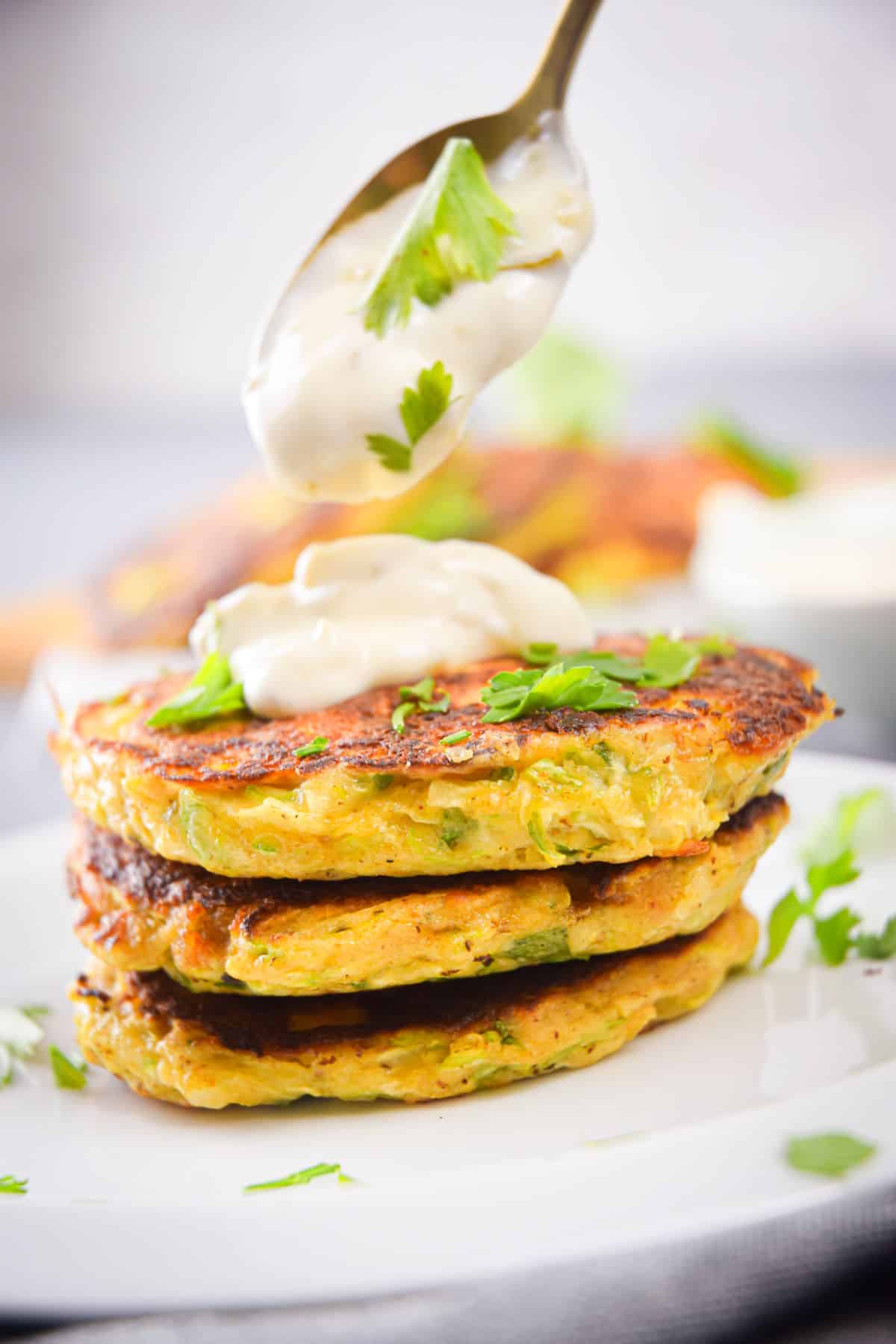 Vegetarian Zucchini Crab Cakes on a white plate with chopped parsley and tartar sauce.