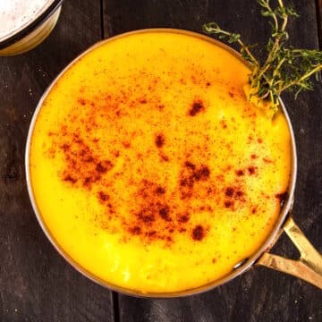 Beer cheese dip in saucepan with paprika and thyme.