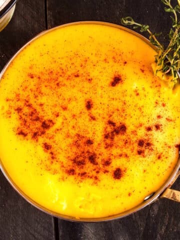 Beer cheese dip in saucepan with paprika and thyme.