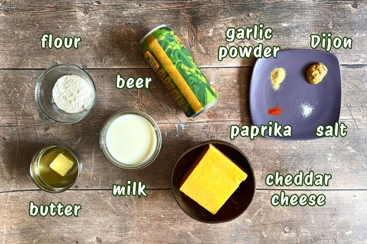 Beer cheese dip ingredients labeled on wooden background.